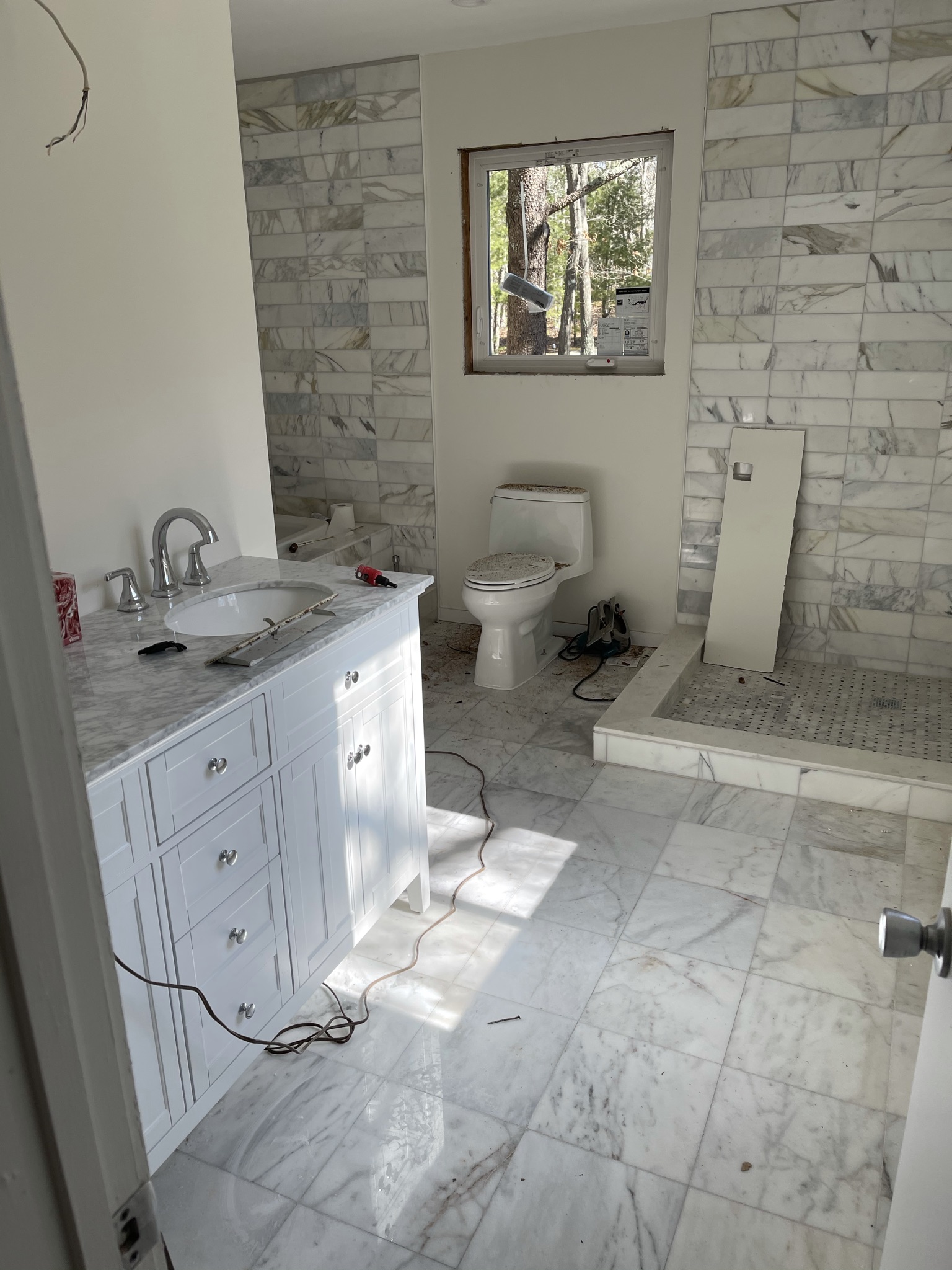 Bathroom near completion — marble floor and vanity installed