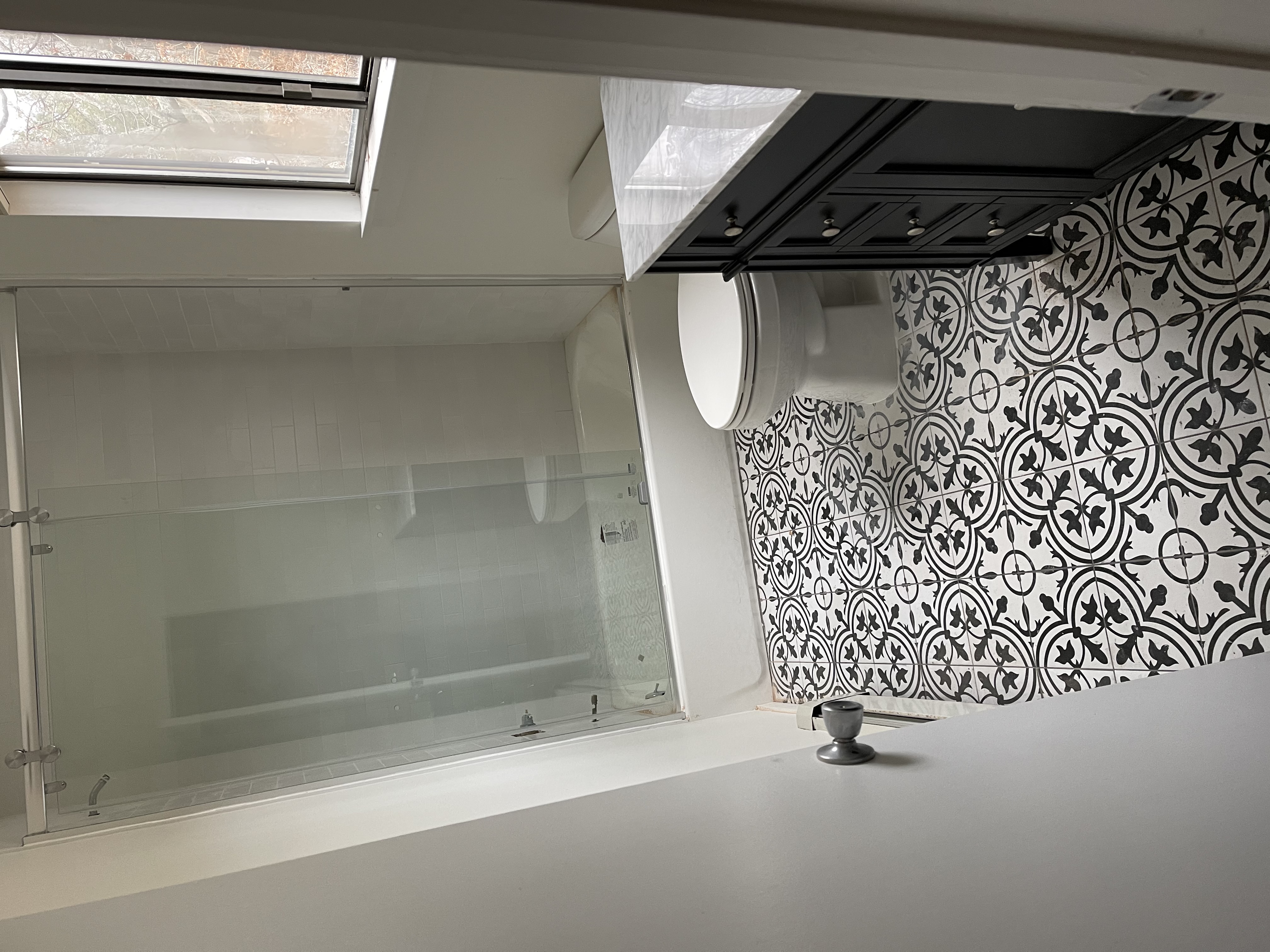 Shower/tub combo with glass door and patterned tile floor