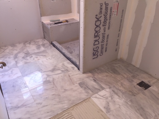 Bathroom during — marble tile floor and shower base being set