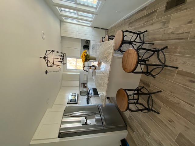 Kitchen after renovation — white shaker cabinets, granite island, pendant light