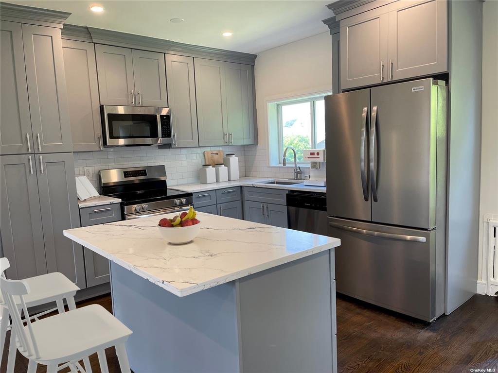 Completed kitchen renovation Long Island — custom gray cabinets, quartz island, stainless appliances